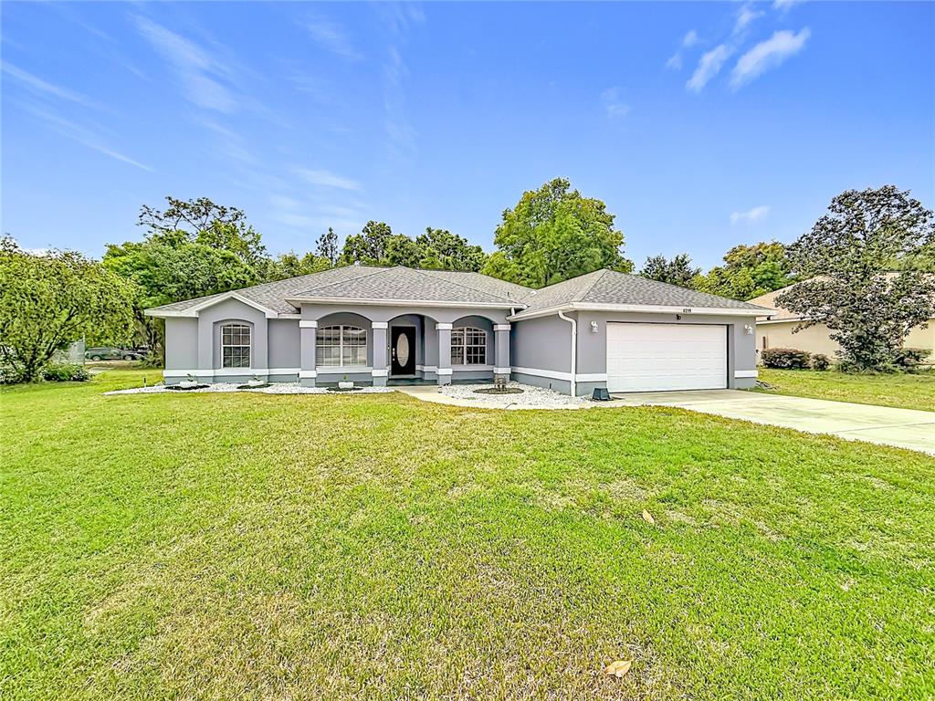 A single-story gray house with a white garage door and a large front lawn — 4319 NW 4TH CIRCLE, OCALA, FL