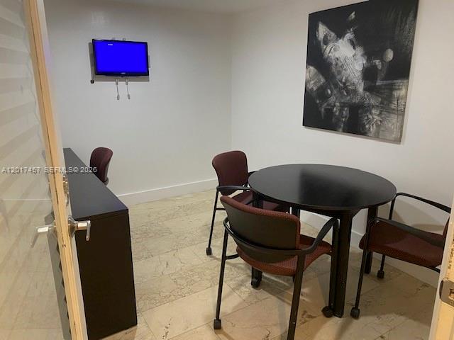 A small office or meeting room features a round table, chairs, and a wall-mounted television — SWEETWATER, FL