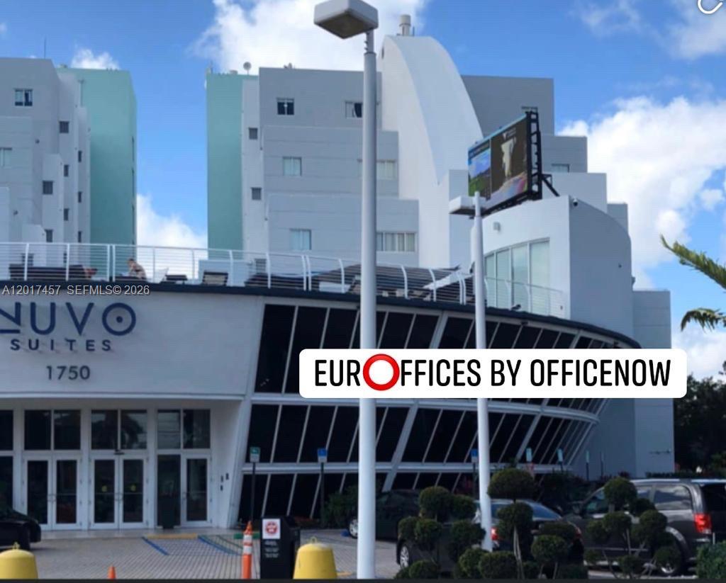 The exterior of a modern multi-story building features a large digital billboard and parking area — SWEETWATER, FL