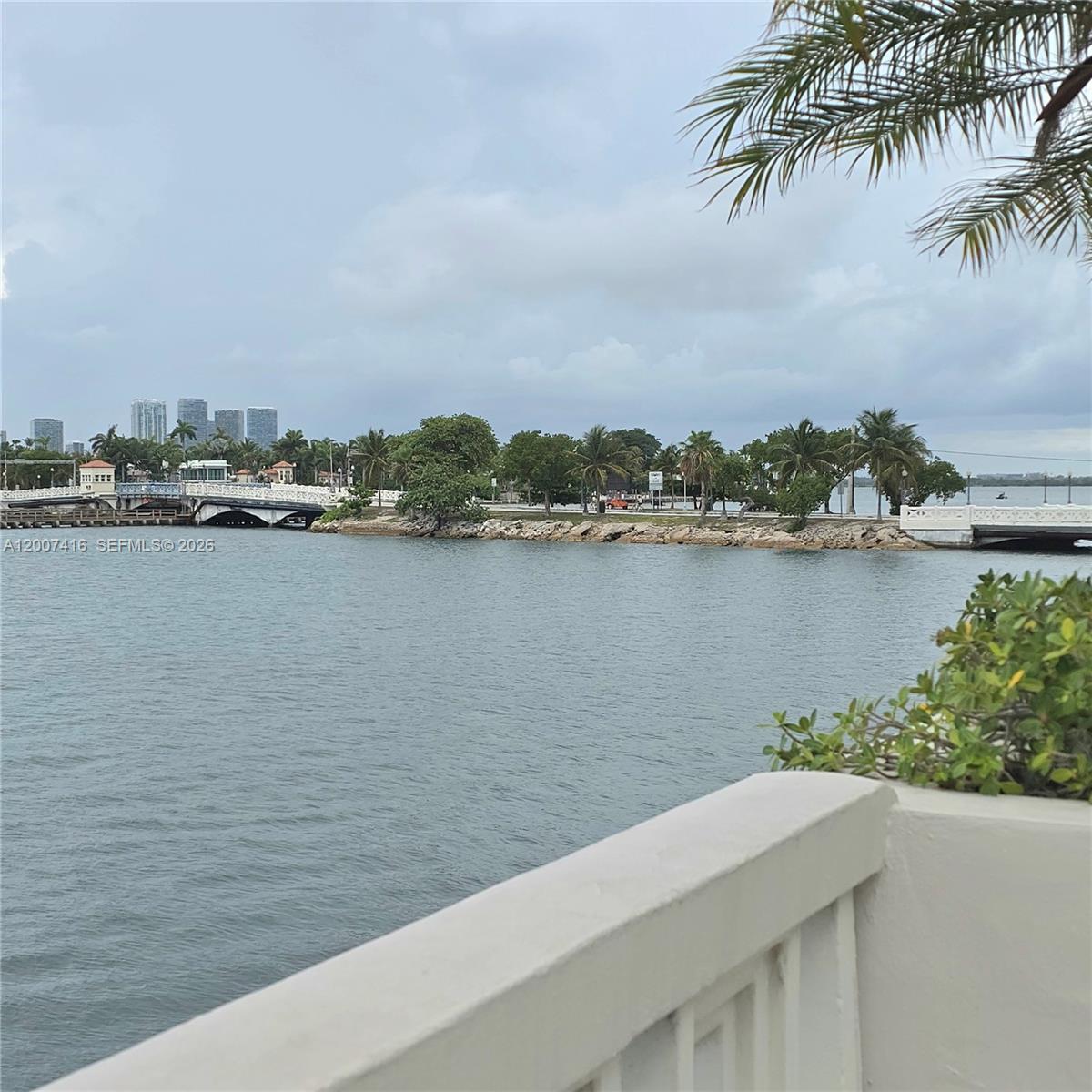 A view of a waterway with bridges, palm trees, and distant city buildings — 5 Island Ave # 5A, Miami Beach FL 33139, MIAMI BEACH, FL