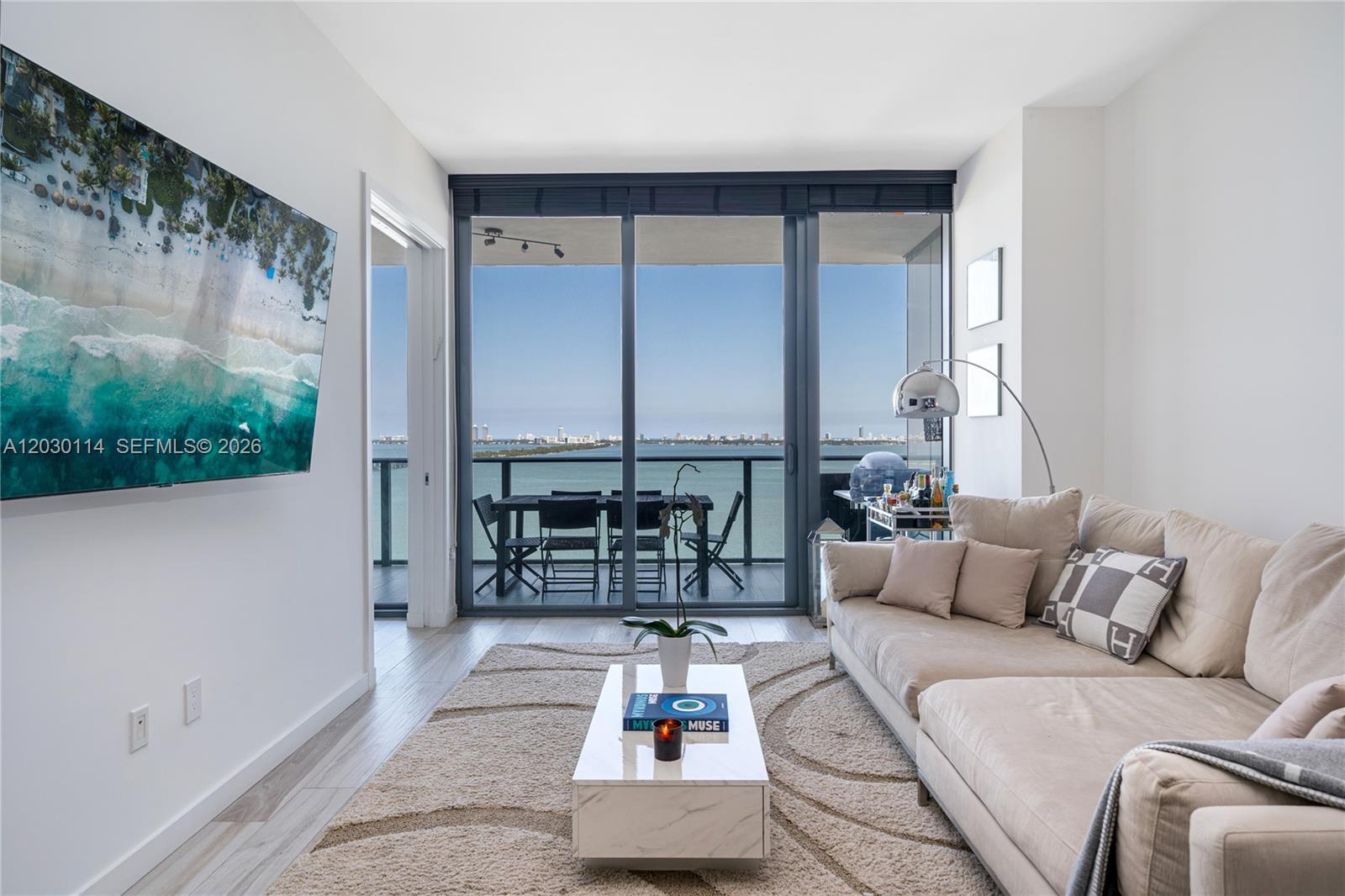 A living room features a beige sectional sofa, a marble coffee table, and a balcony view — 480 NE 31st St # 1603, Miami FL 33137, MIAMI, FL