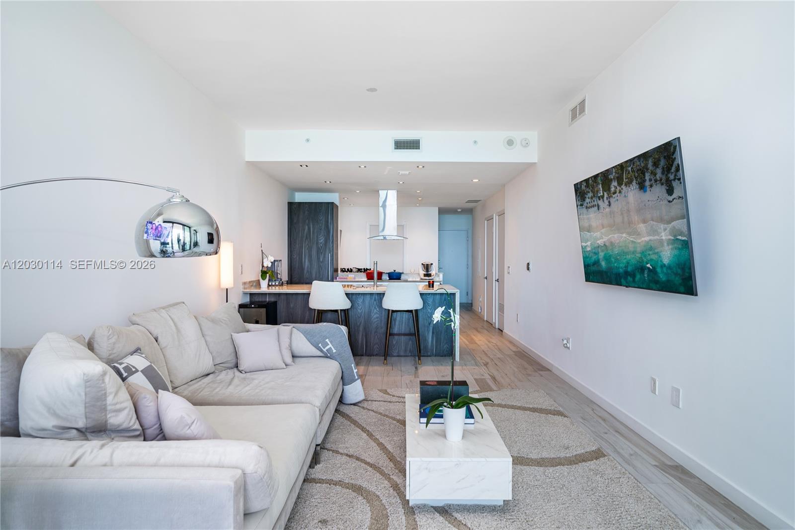 A modern living room features a sectional sofa, a coffee table, and an open kitchen — 480 NE 31st St # 1603, Miami FL 33137, MIAMI, FL