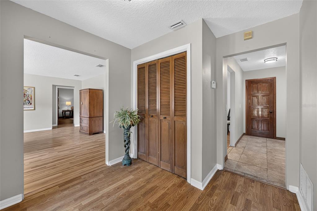 A hallway with wood flooring, a louvered closet door, and an arched entryway to another room — 551 RYLANE STREET, DE LEON SPRINGS, FL