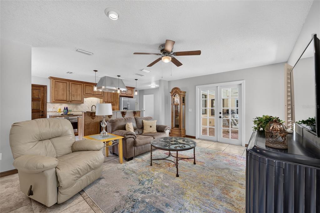 A living room features a beige recliner, brown sofa, coffee table, and an open kitchen — 551 RYLANE STREET, DE LEON SPRINGS, FL