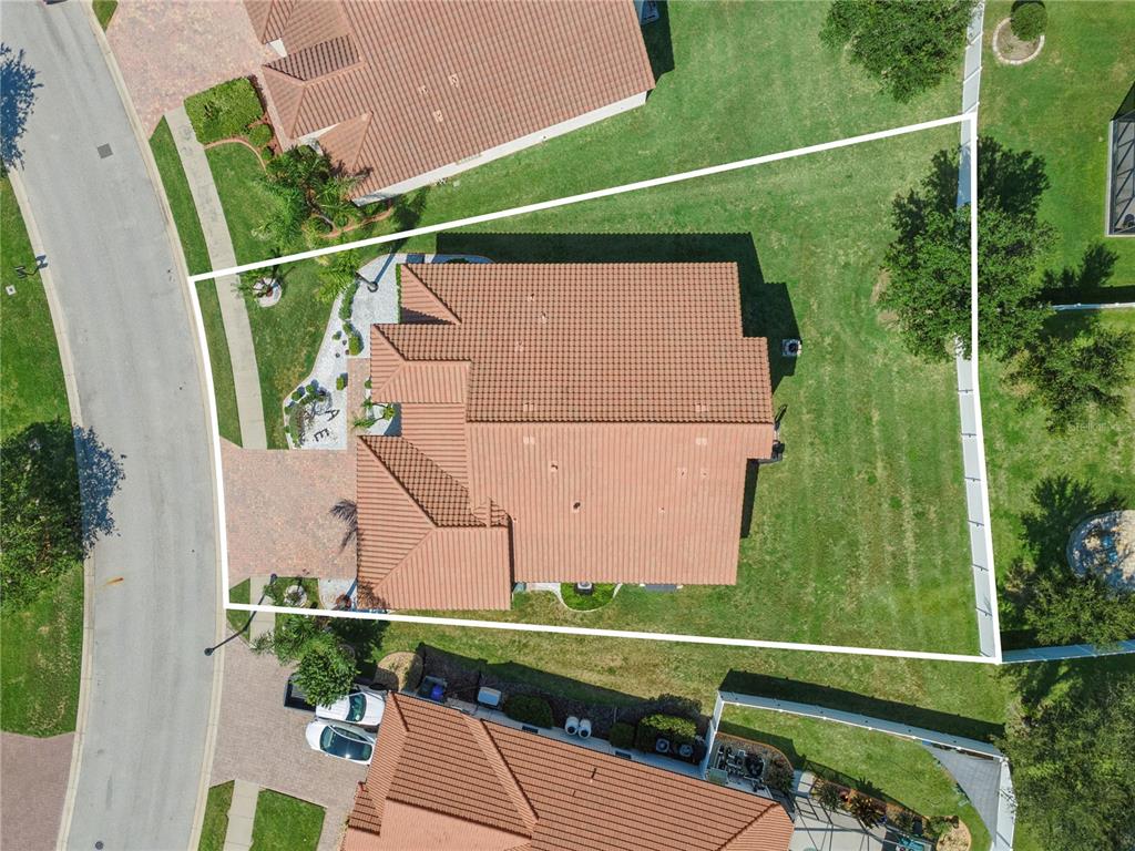 An aerial view shows a house with a tiled roof situated on a corner lot — 3943 SUNSET LAKE DRIVE, LAKELAND, FL
