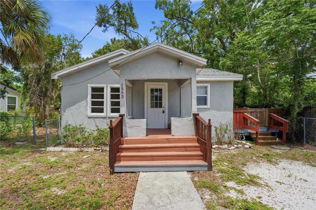 A small, light gray house with a front porch, wooden steps, and a gravel yard — 1553 29TH STREET, SARASOTA, FL