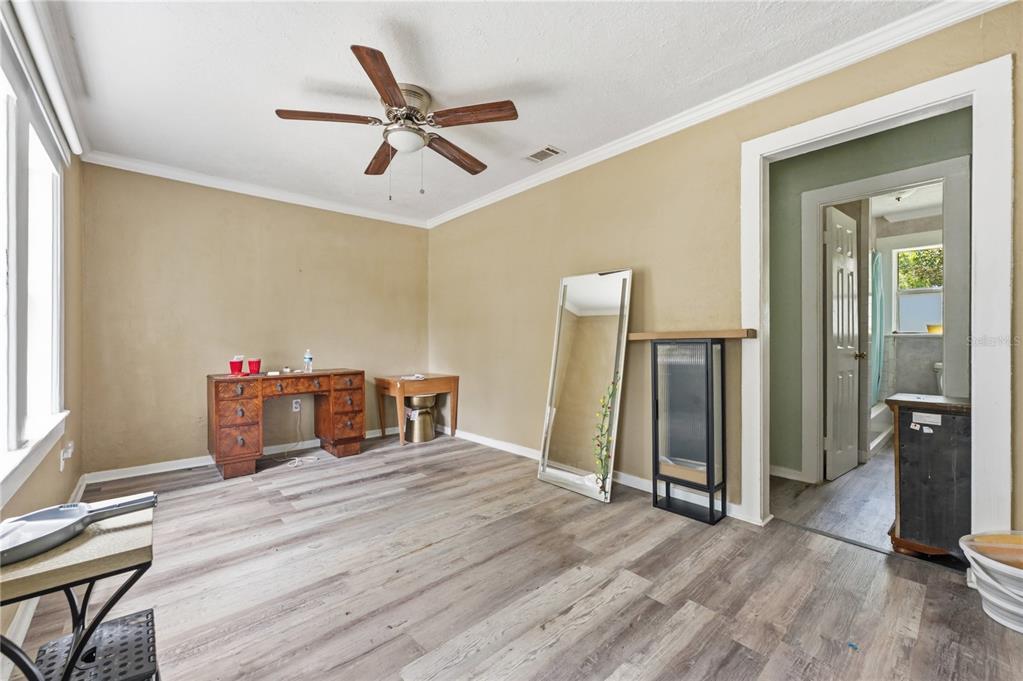 A room with wood-look flooring, a ceiling fan, a desk, a mirror, and a doorway — 1553 29TH STREET, SARASOTA, FL