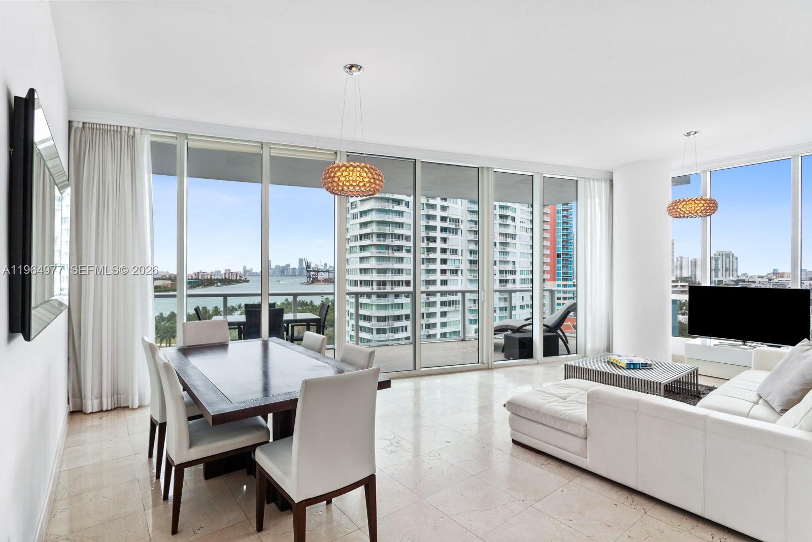 A bright living and dining area features floor-to-ceiling windows with views of the water — 100 S Pointe Dr # 1001, Miami Beach FL 33139, MIAMI BEACH, FL