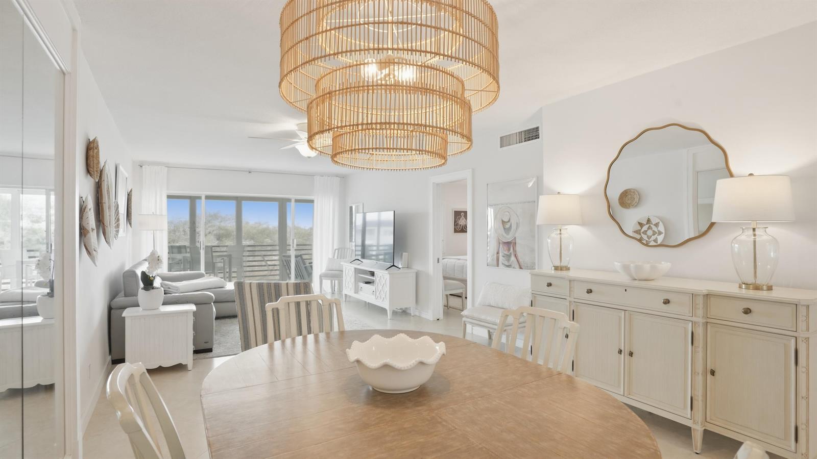 A dining area with a large rattan chandelier overlooks a living room and balcony — 921 Spanish Circle # 436, Delray Beach FL 33483, DELRAY BEACH, FL