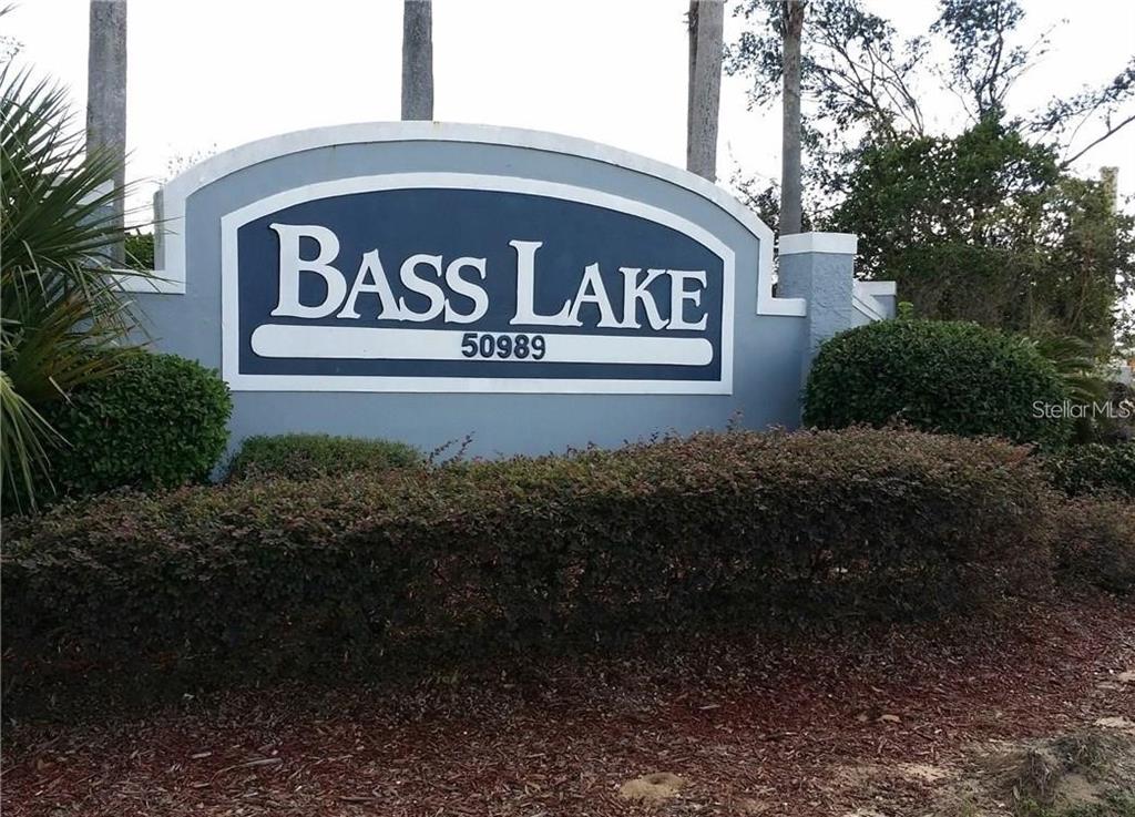 A blue and white neighborhood entrance sign reads Bass Lake with the number 50989 below — 50989 HIGHWAY 27 UNIT 79, DAVENPORT, FL