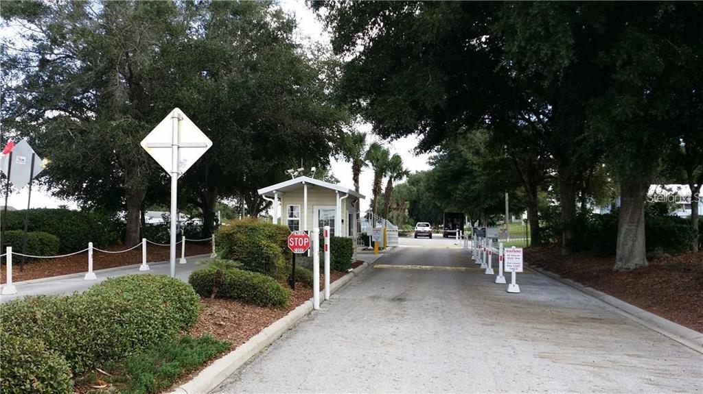 A gated community entrance features a guardhouse, a stop sign, and a paved driveway — 50989 HIGHWAY 27 UNIT 79, DAVENPORT, FL