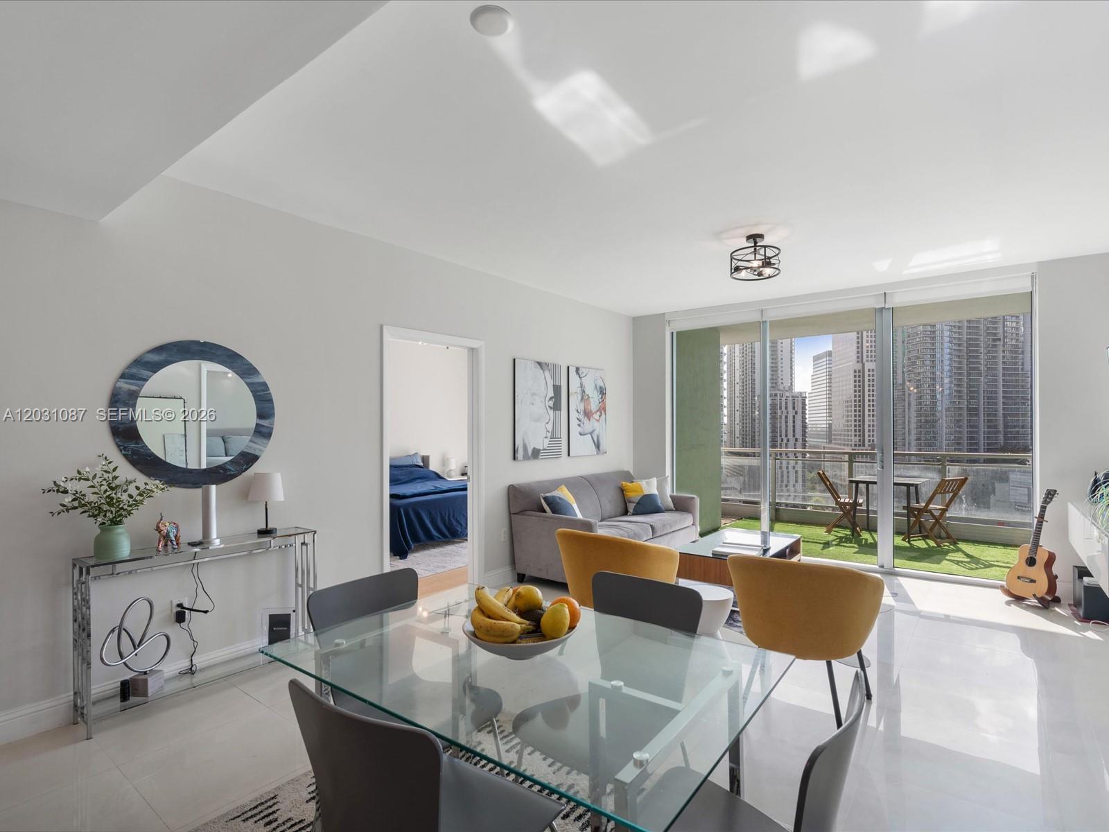 A modern living and dining area features a glass table, yellow chairs, and a balcony — 90 SW 3rd St # 2015, Miami FL 33130, MIAMI, FL