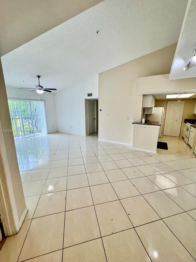 A bright, open-concept living area features light-colored tile flooring and an adjacent kitchen — ROYAL PALM BEACH, FL