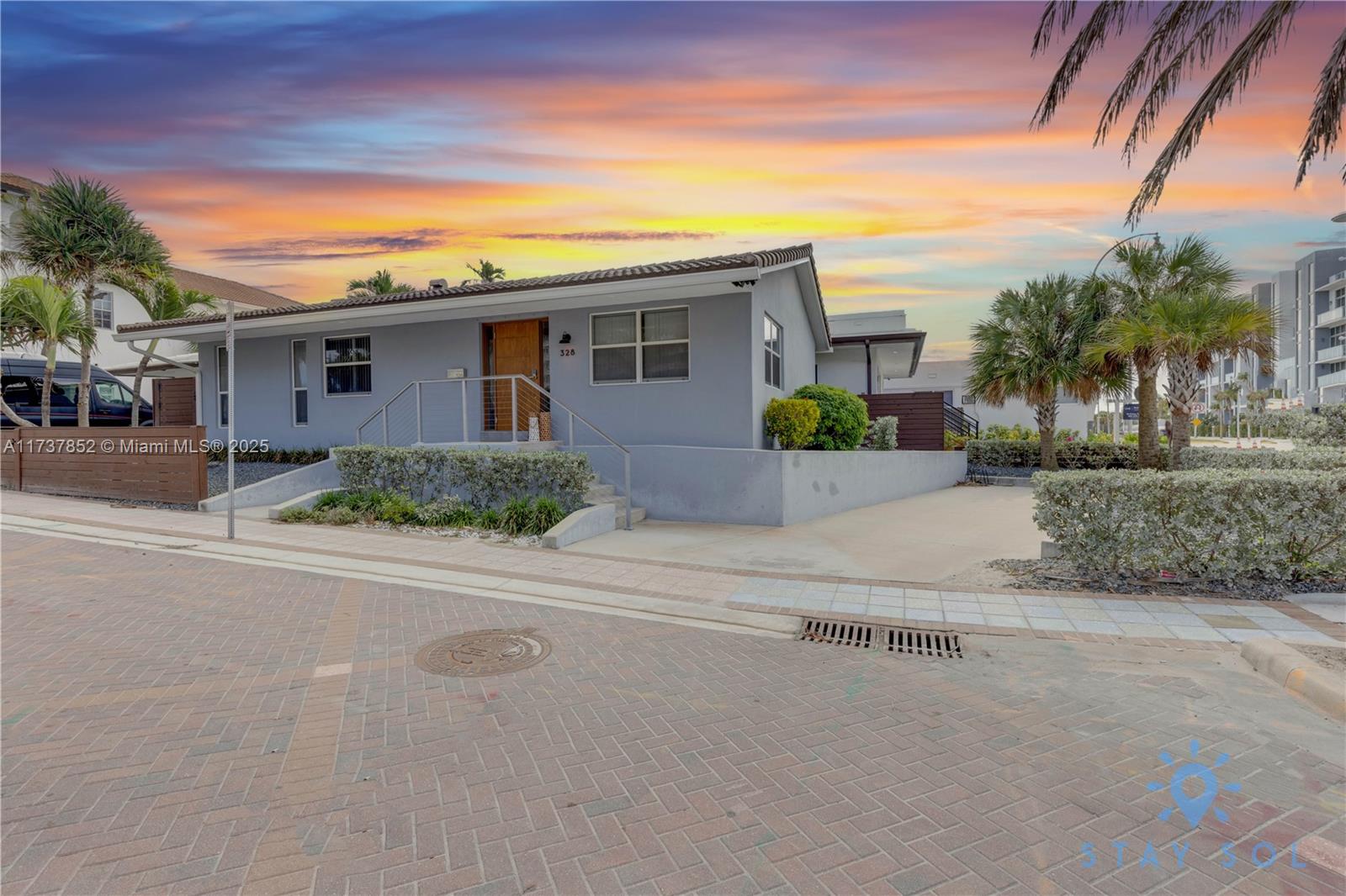A single-story gray house with a wooden front door and a paved driveway at sunset — 328 Missouri St, Hollywood FL 33019, HOLLYWOOD, FL