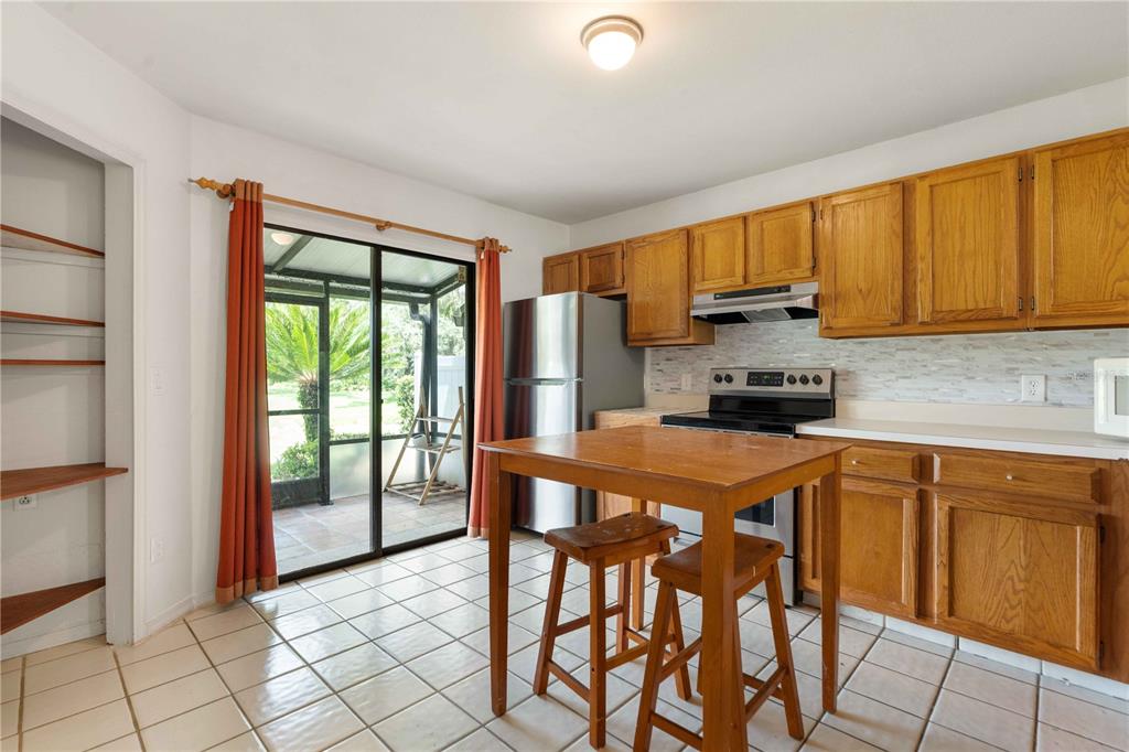 A kitchen with oak cabinets, tile flooring, a small dining table, and a sliding glass door — 5100 BURCHETTE ROAD UNIT 404, TAMPA, FL