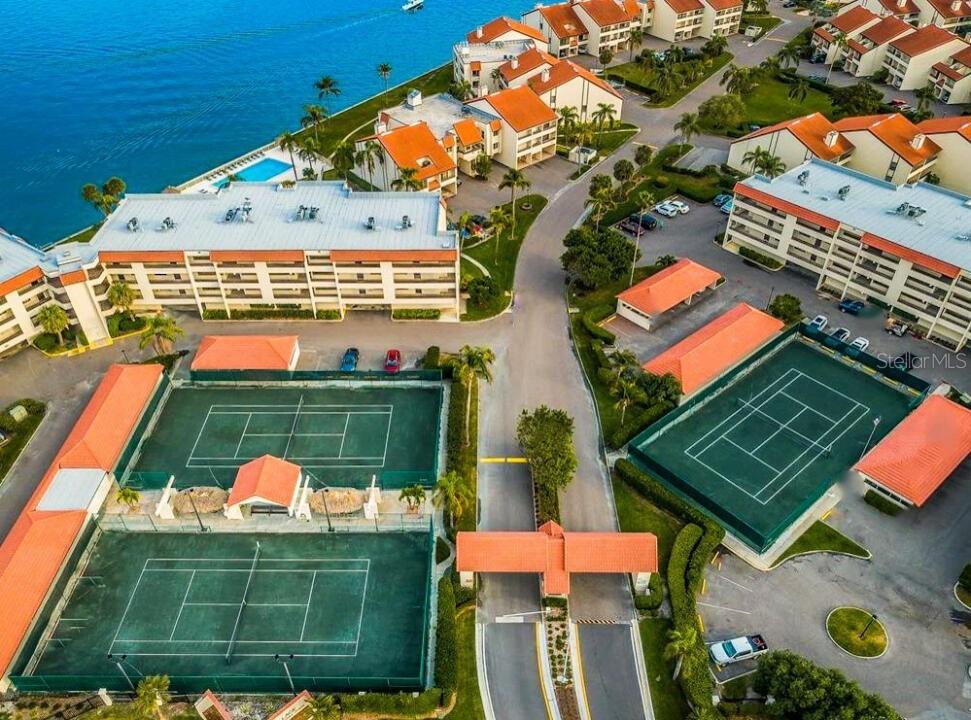 Aerial view of a residential complex featuring tennis courts, swimming pools, and multi-story buildings — 106 1ST STREET E UNIT 215, ST PETERSBURG, FL