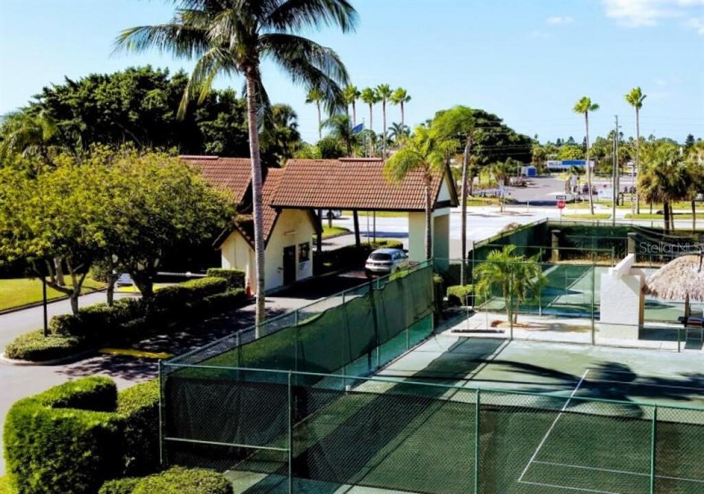 An outdoor view of a gated entrance with a guardhouse next to a tennis court — 106 1ST STREET E UNIT 215, ST PETERSBURG, FL