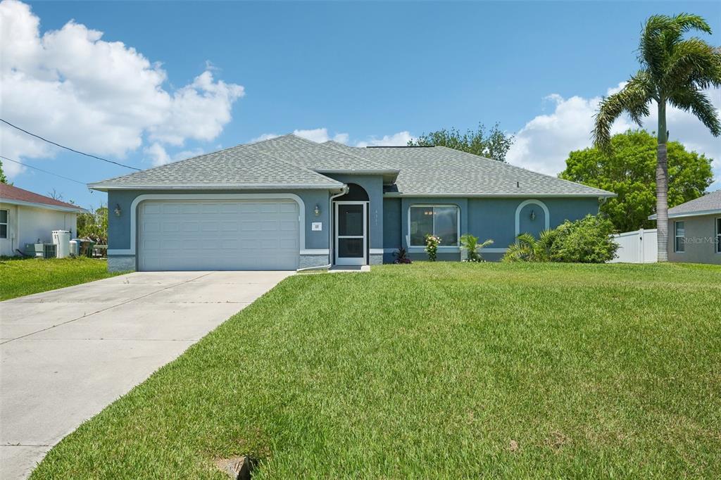 A single-story blue house with a two-car garage and a front lawn under a sky — 4317 NW 40TH TERRACE, CAPE CORAL, FL