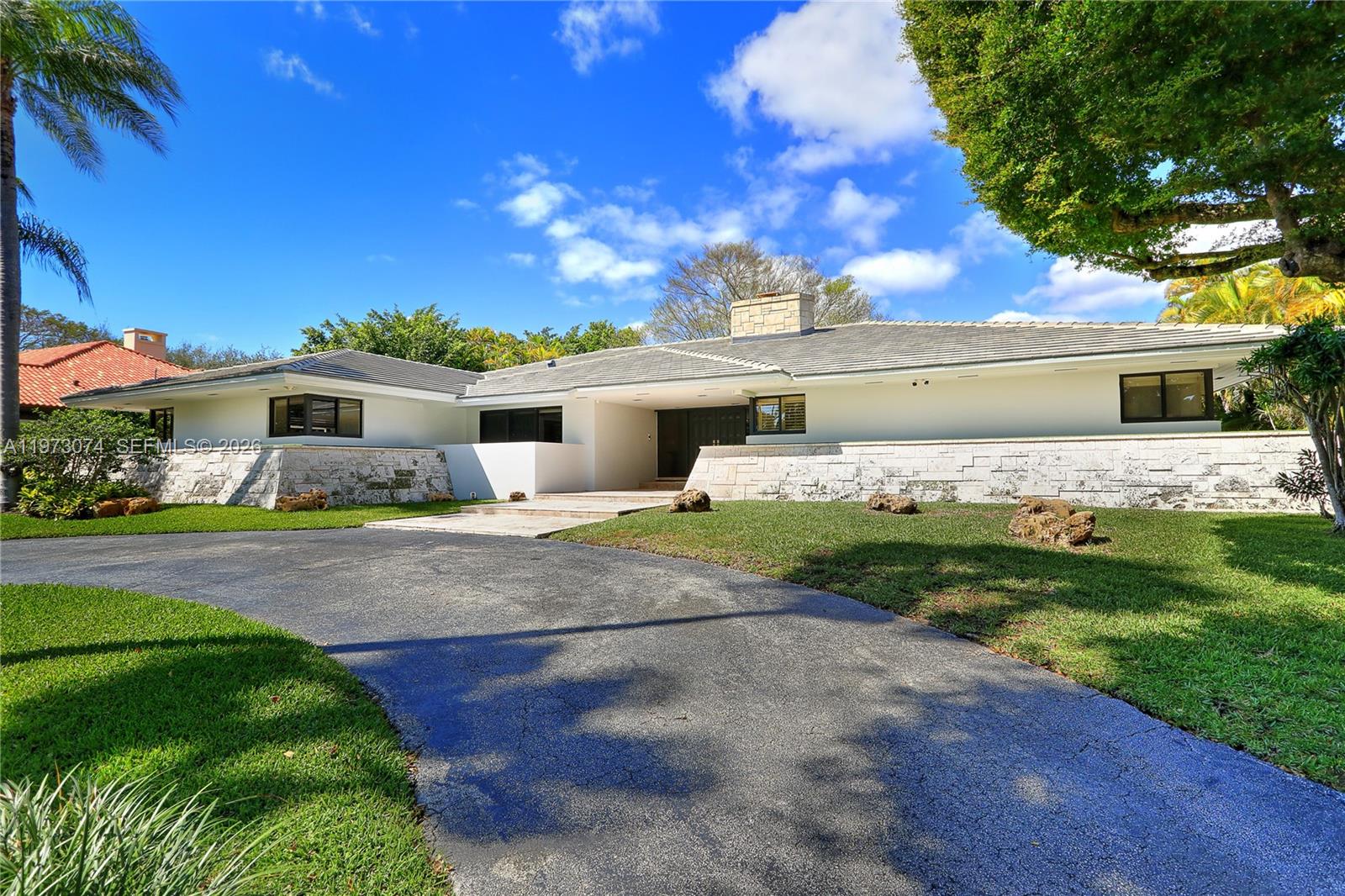 A single-story house with a stone facade and a curved driveway under a blue sky — 7322 Vistalmar St, Coral Gables FL 33143, CORAL GABLES, FL