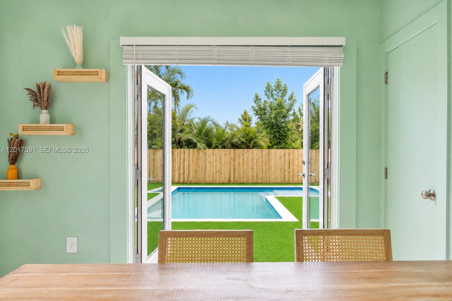 A dining area with light green walls overlooks a backyard swimming pool through open doors — 22 NE 44th St, Miami FL 33137, MIAMI, FL