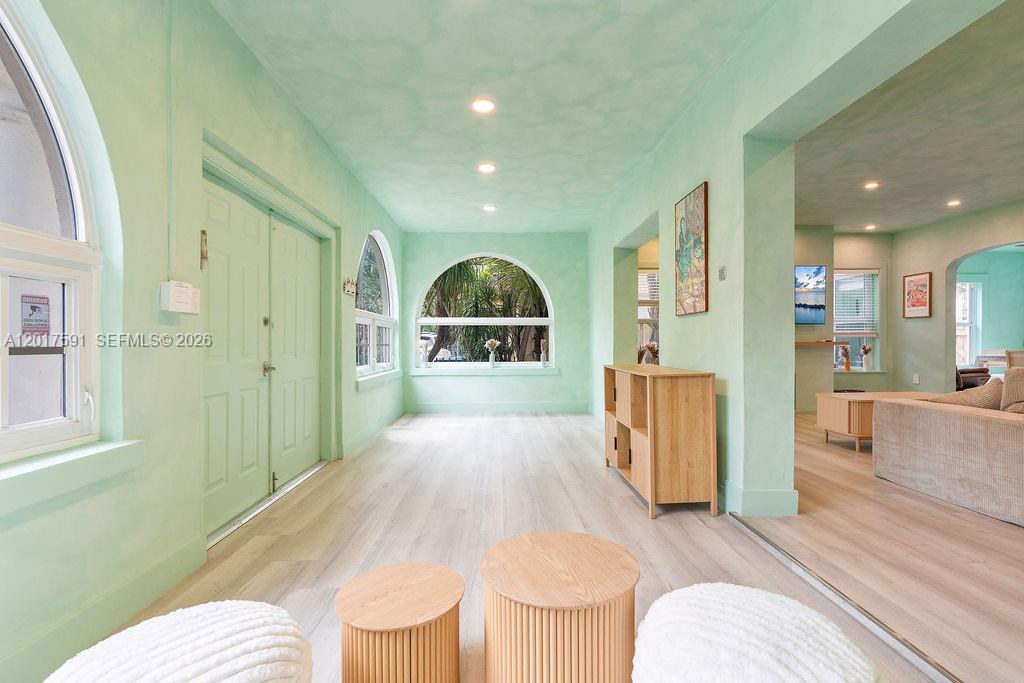 A light green sunroom features arched windows, light wood flooring, and recessed ceiling lighting — 22 NE 44th St, Miami FL 33137, MIAMI, FL
