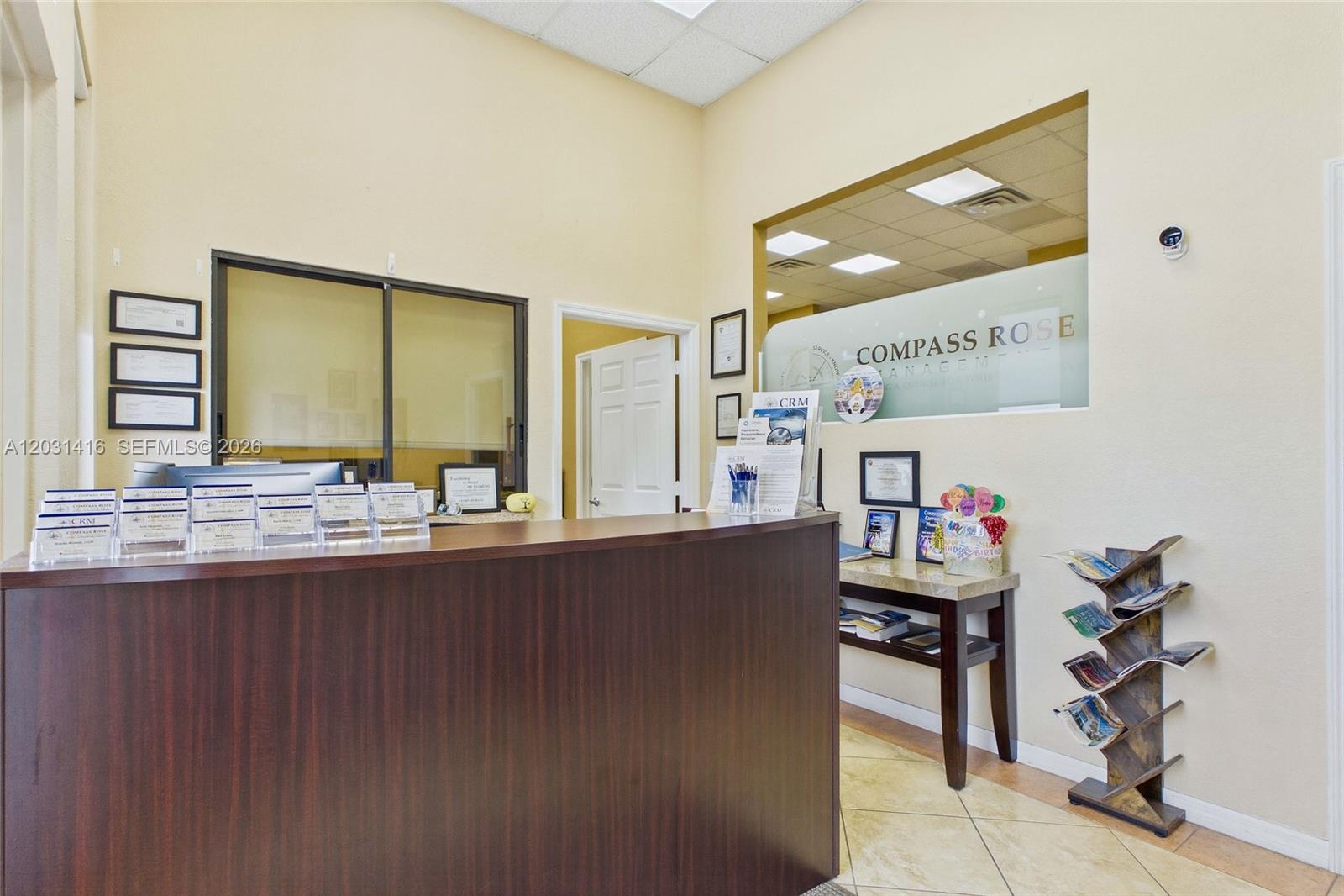 A reception area features a dark wood desk, tile flooring, and a glass-partitioned office wall — CAPE CORAL, FL