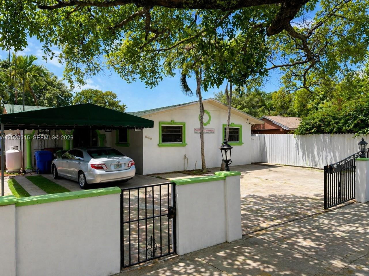 A single-story house with a green-trimmed exterior, a carport, and a gated concrete driveway — 610 SW 66th Ave, Miami FL 33144, MIAMI, FL