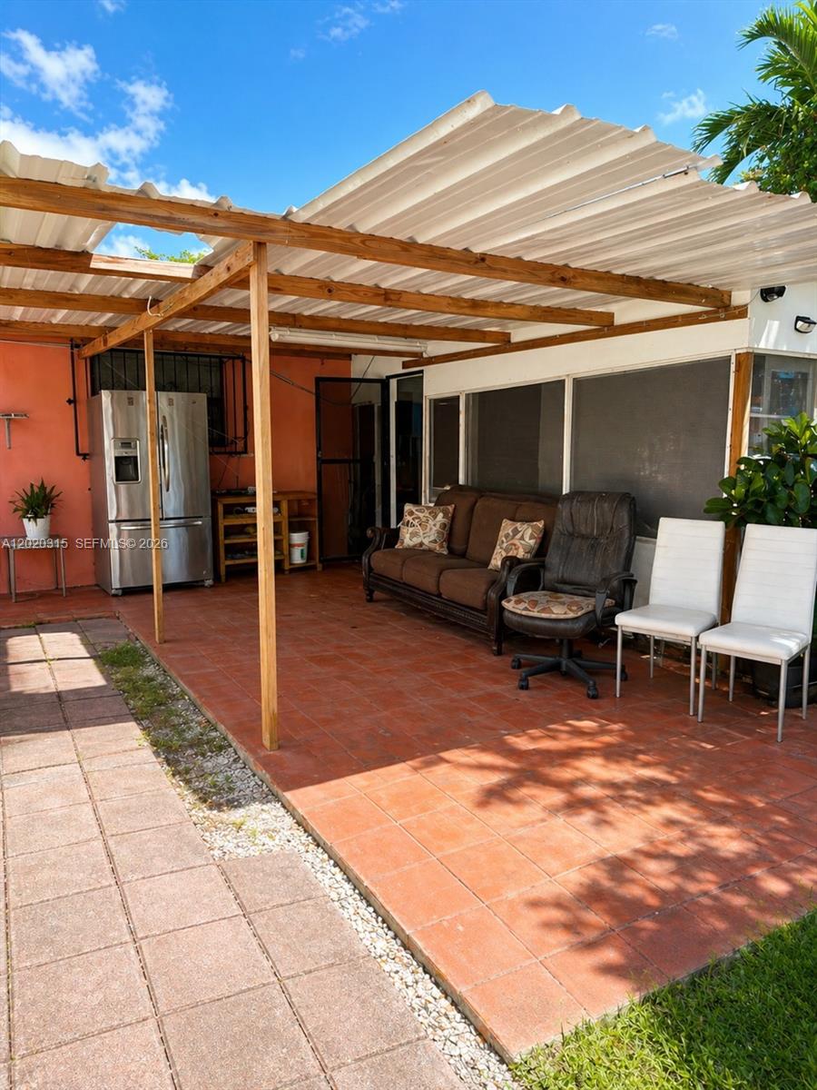 A covered outdoor patio features a tiled floor, a sofa, chairs, and a refrigerator — 610 SW 66th Ave, Miami FL 33144, MIAMI, FL