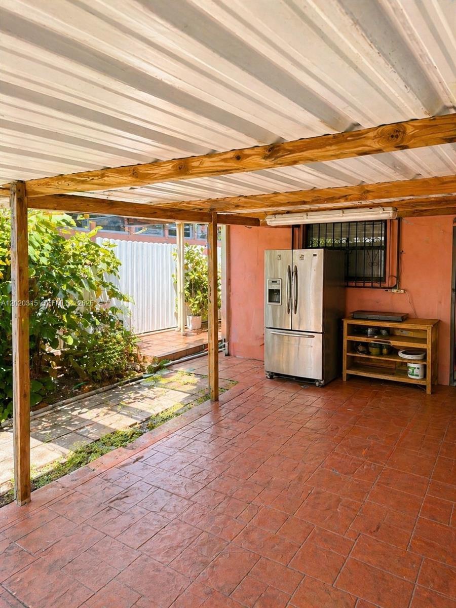 A covered outdoor patio features a stamped concrete floor, a stainless steel refrigerator, and shelving — 610 SW 66th Ave, Miami FL 33144, MIAMI, FL