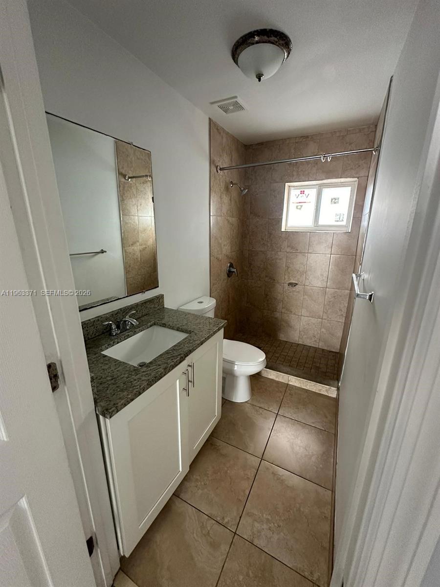 A bathroom features a granite-topped vanity, a tiled walk-in shower, and a white toilet — 1128 NW 101st St, Miami FL 33150, MIAMI, FL