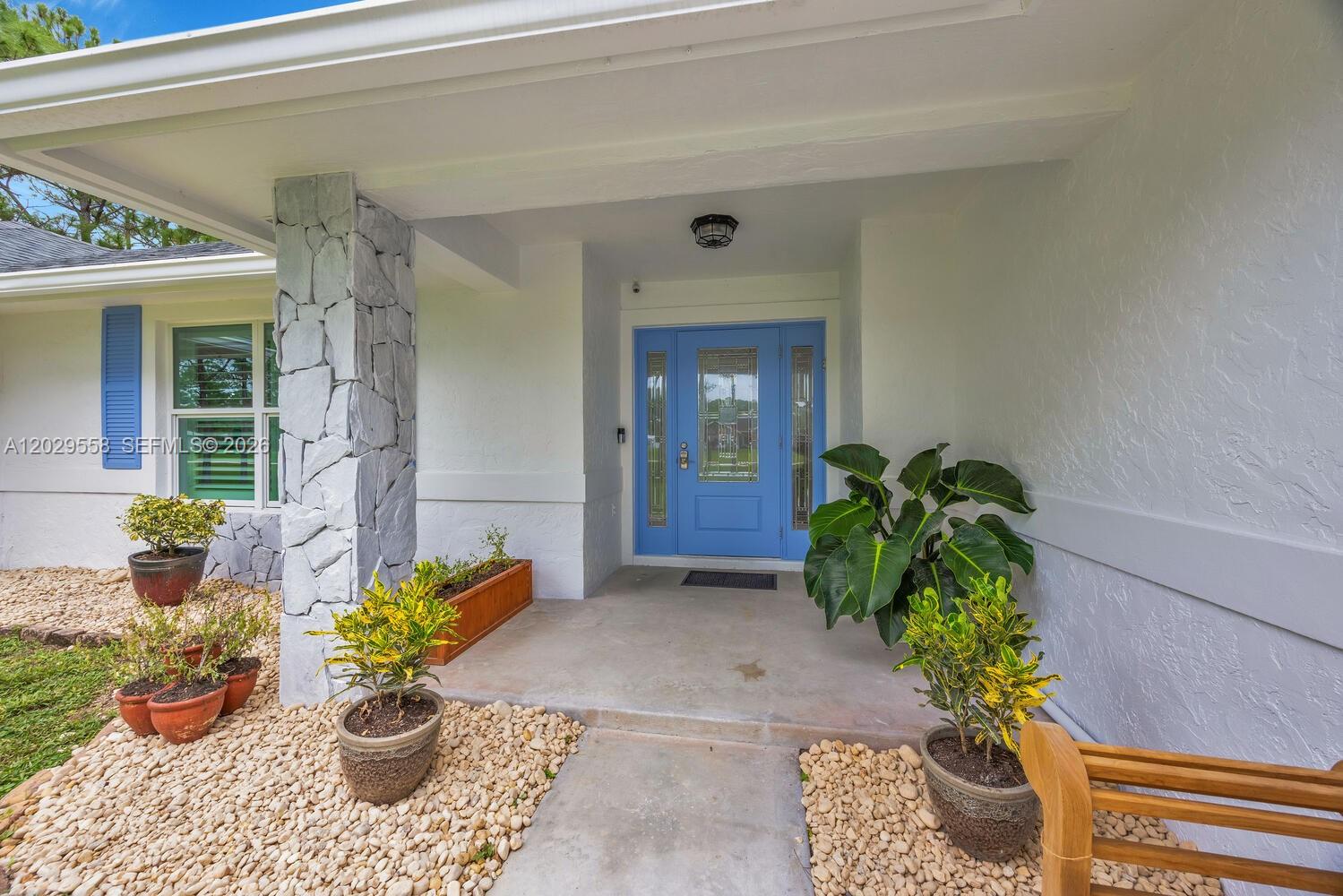 A gravel driveway leads to a single-story house and a detached garage among pine trees — 17107 N 84th Ct N, Loxahatchee FL 33470, LOXAHATCHEE, FL