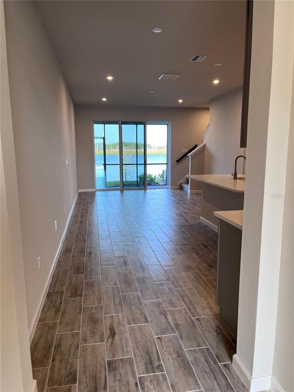 A view of a living area with wood-look tile flooring leading to a sliding glass door — 2345 SUMMERLIT STREET, LUTZ, FL