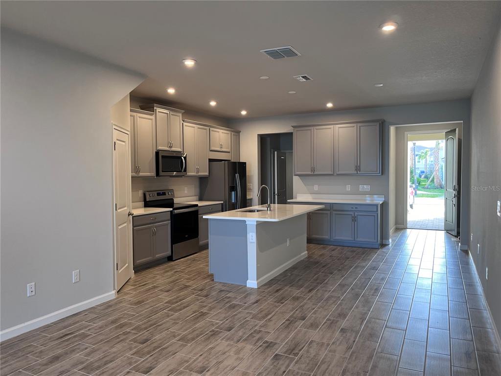 A modern kitchen features gray cabinets, a central island, and wood-look tile flooring — 2345 SUMMERLIT STREET, LUTZ, FL