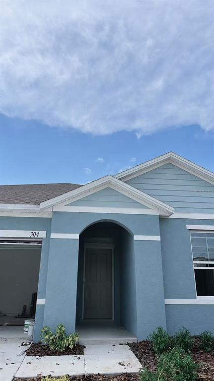 A light blue house exterior features a covered entryway, a garage, and a front window — 304 SOFIA LANE, LAKE ALFRED, FL