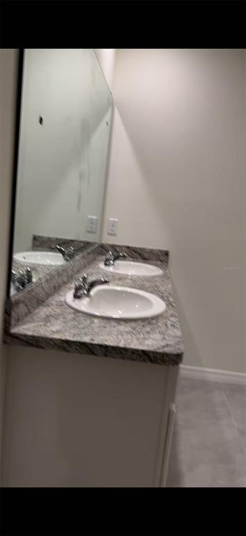 A bathroom vanity with a granite countertop, two sinks, and a large wall mirror — 304 SOFIA LANE, LAKE ALFRED, FL