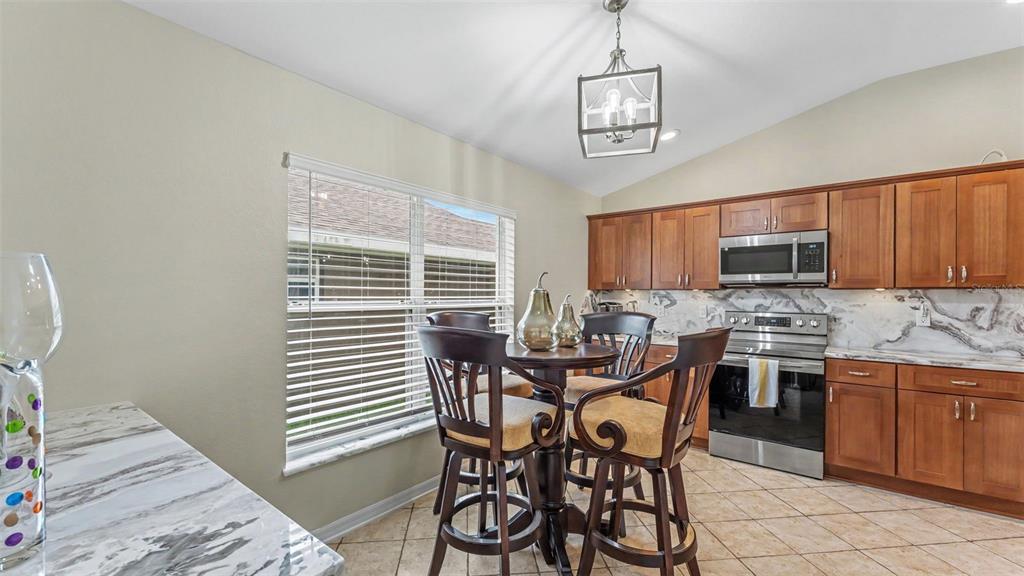 A kitchen with wood cabinets, stainless steel appliances, and a small dining table — 6838 SHIMMERING DRIVE, LAKELAND, FL