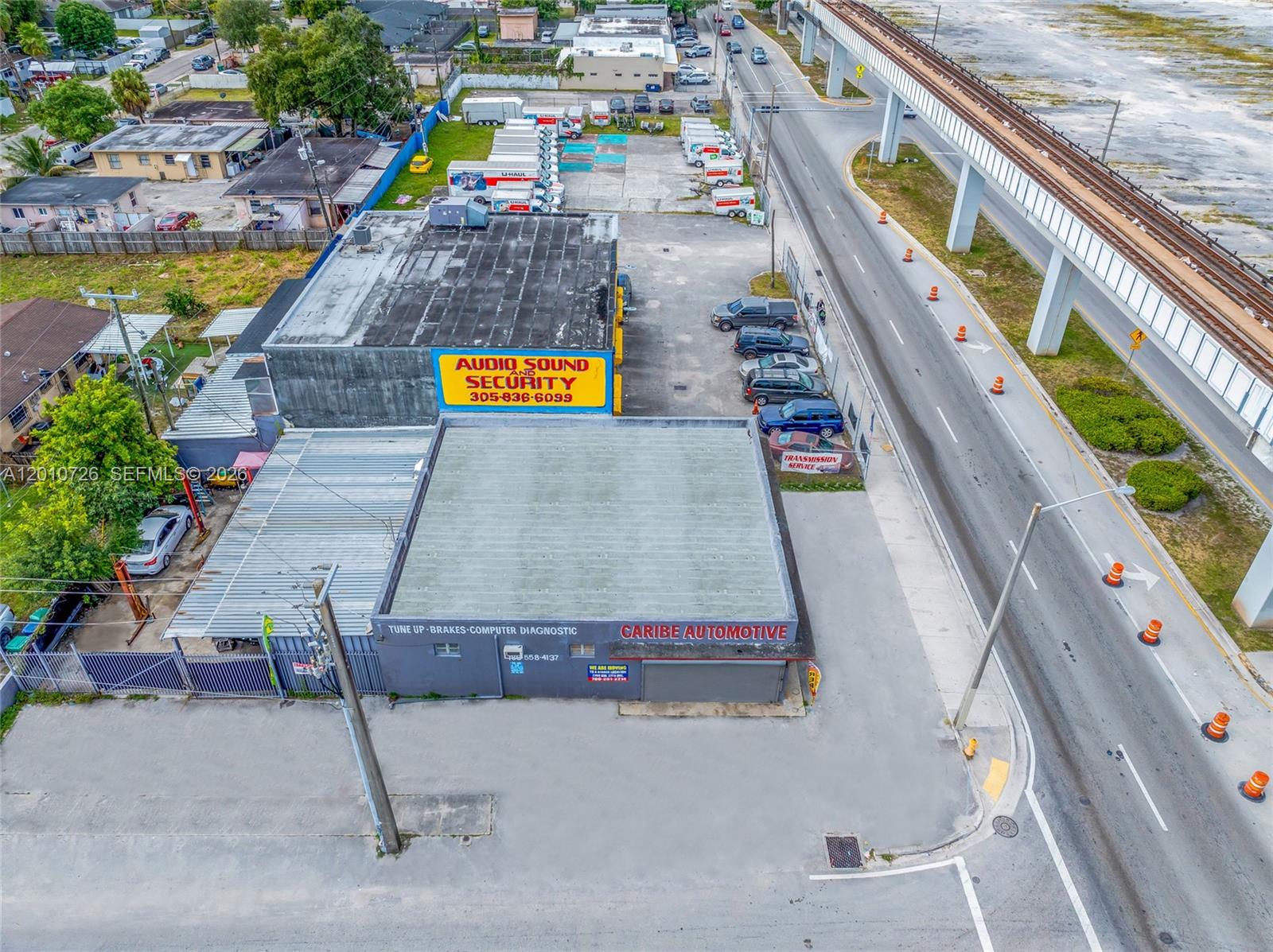 An aerial view shows two commercial buildings with parking lots next to an elevated railway — 3000 NW 79th St, Miami FL 33147, MIAMI, FL
