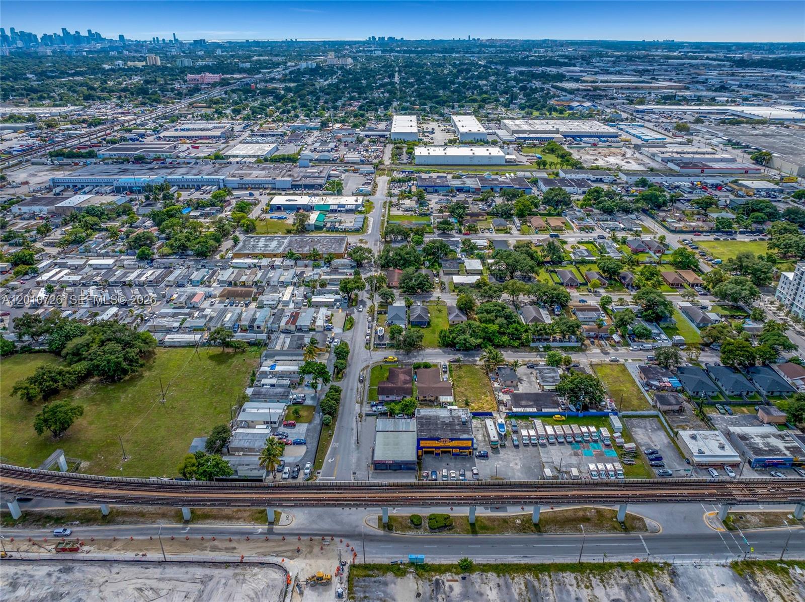 An aerial view shows a commercial building and residential area adjacent to an elevated train track — 3000 NW 79th St, Miami FL 33147, MIAMI, FL