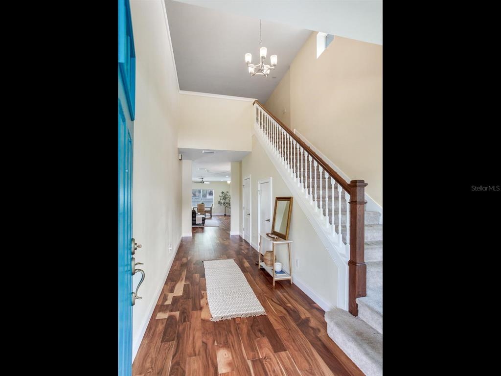 A bright entryway features wood floors, a staircase with white railings, and a blue door — 3204 W LEMON STREET, TAMPA, FL