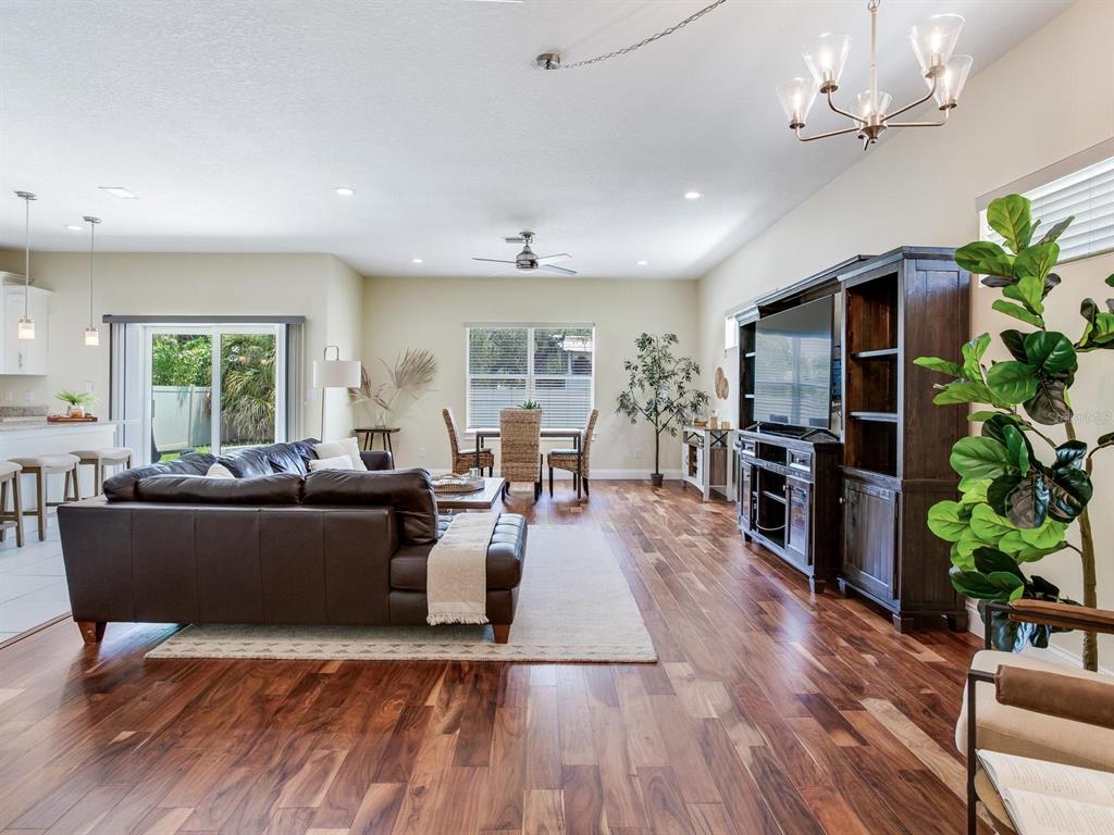 A living room with dark wood floors, a leather sectional, and a large media console — 3204 W LEMON STREET, TAMPA, FL