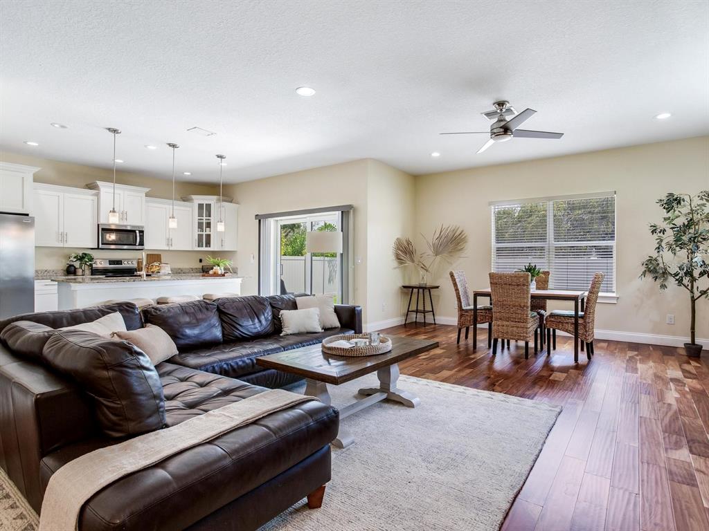 An open-concept living room and kitchen feature a leather sectional, dining set, and hardwood floors — 3204 W LEMON STREET, TAMPA, FL