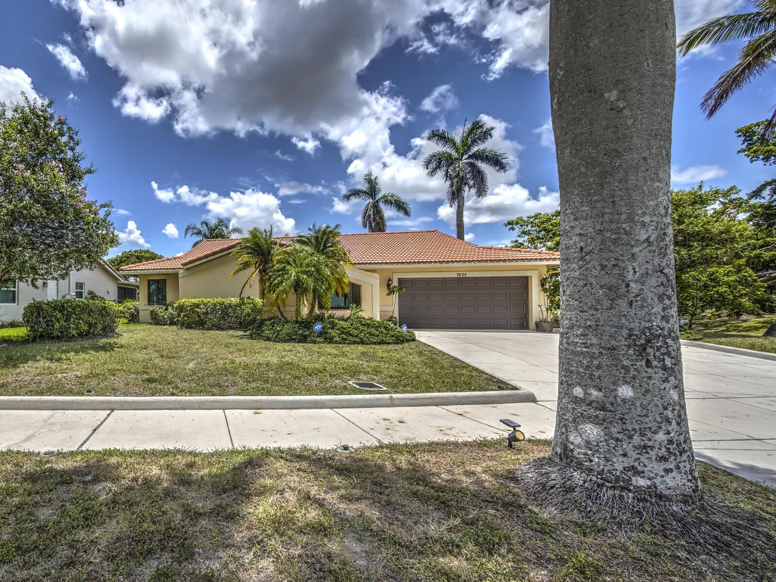 A single-story house with a tile roof, brown garage door, and palm trees in front — 7625 Sunflower Drive, Margate FL 33063, MARGATE, FL