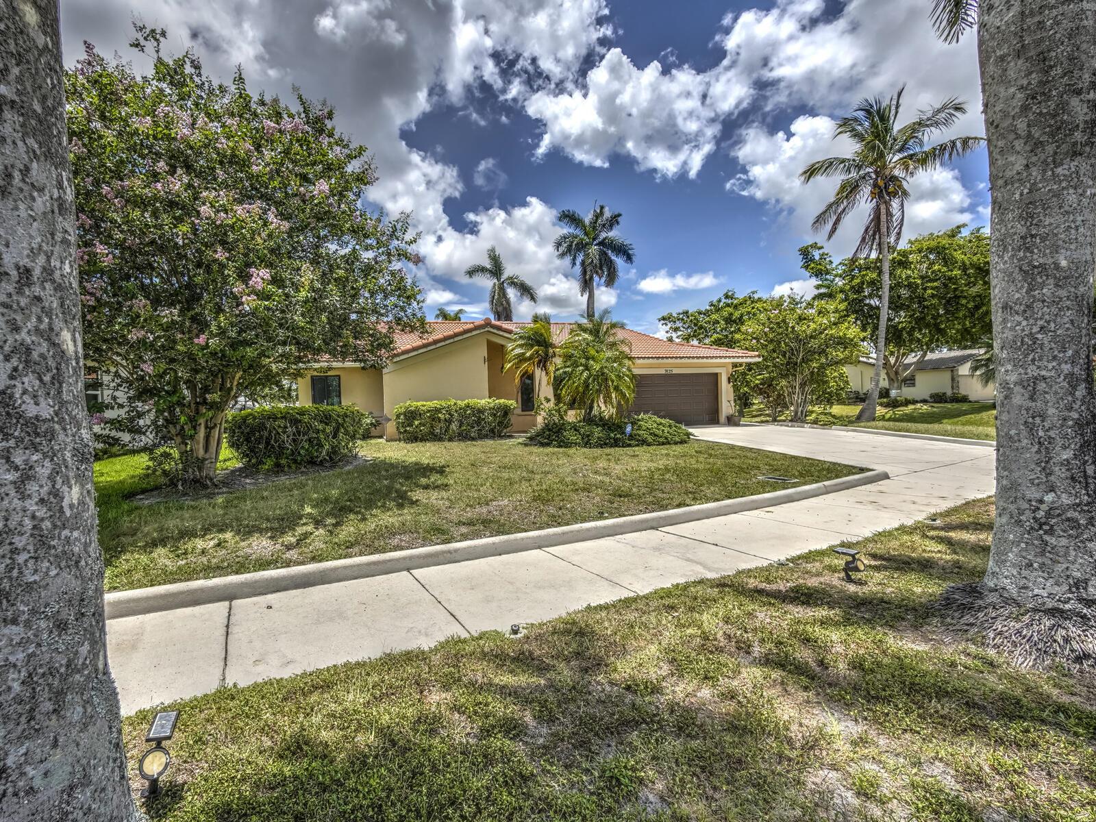 A single-story house with a tile roof and a driveway sits behind a grassy lawn — 7625 Sunflower Drive, Margate FL 33063, MARGATE, FL