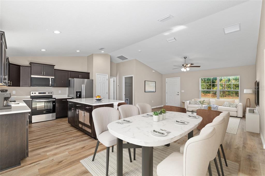 An open-concept kitchen and dining area featuring dark cabinetry, a kitchen island, and wood flooring — 8442 N TEMPEST DRIVE, CITRUS SPRINGS, FL