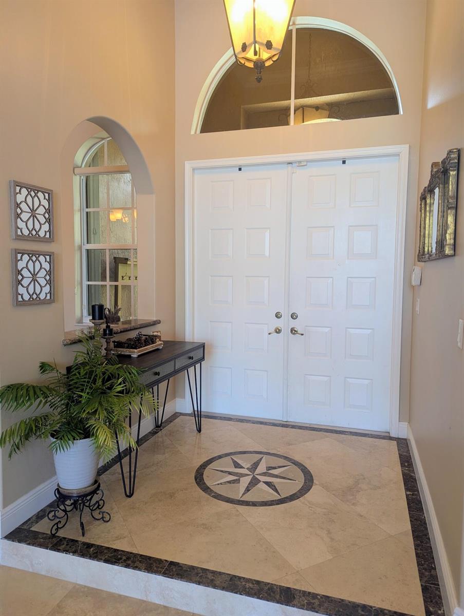 A bright entryway features double white doors, a tiled floor with a compass inlay, and windows — 10640 Oak Meadow Lane, Lake Worth FL 33449, LAKE WORTH, FL