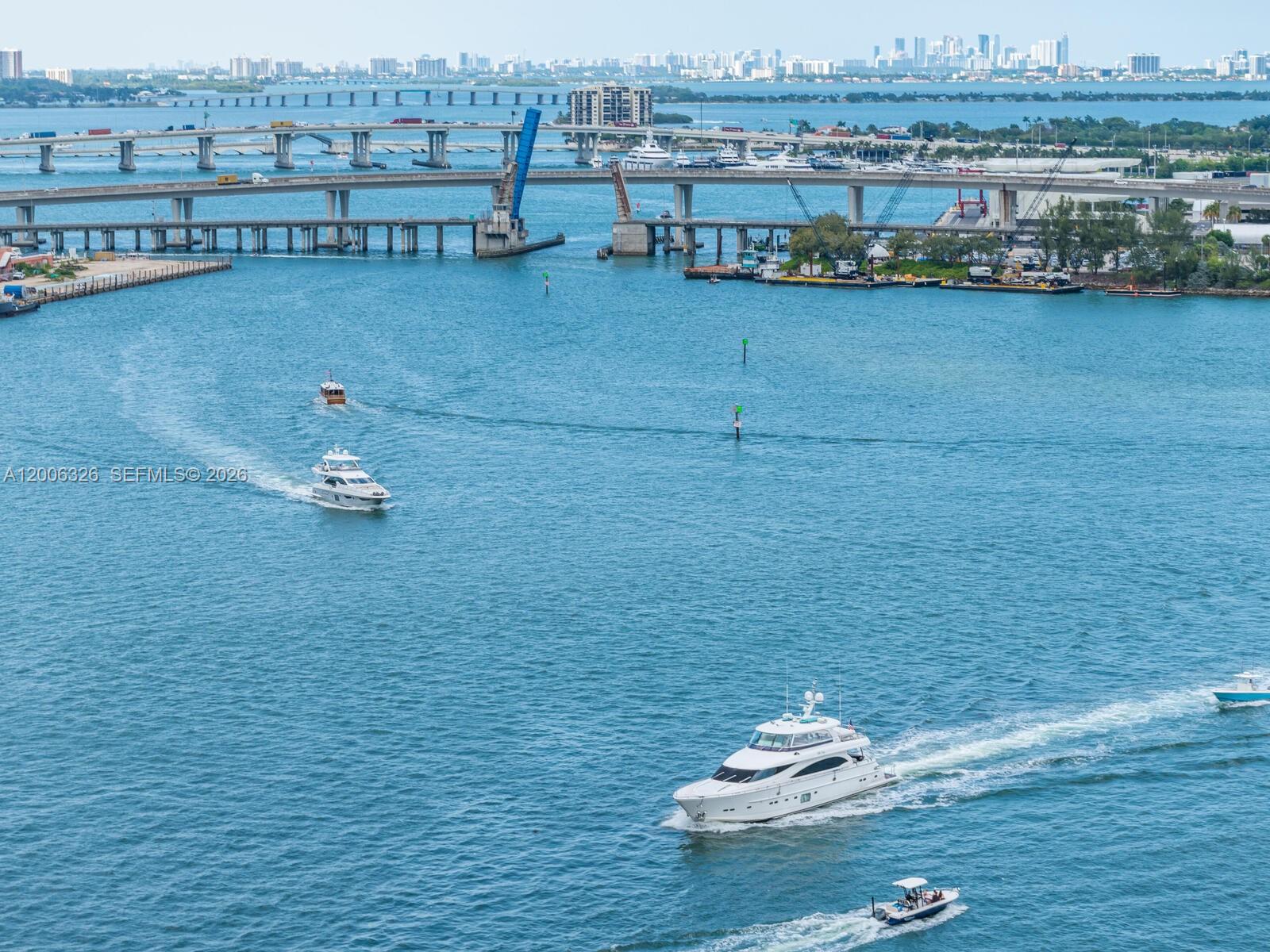An aerial view shows boats traveling on a waterway beneath a large highway bridge — 888 Brickell Key Dr # 2112, Miami FL 33131, MIAMI, FL
