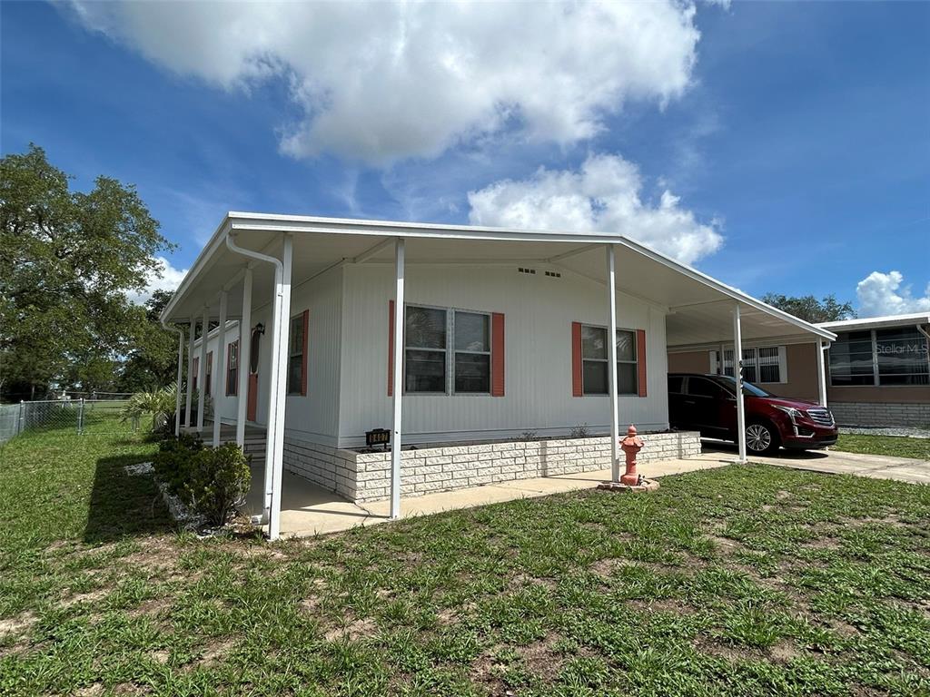 A white manufactured home with a brick-patterned base and a covered carport — 8407 WEATHERFORD AVENUE, BROOKSVILLE, FL