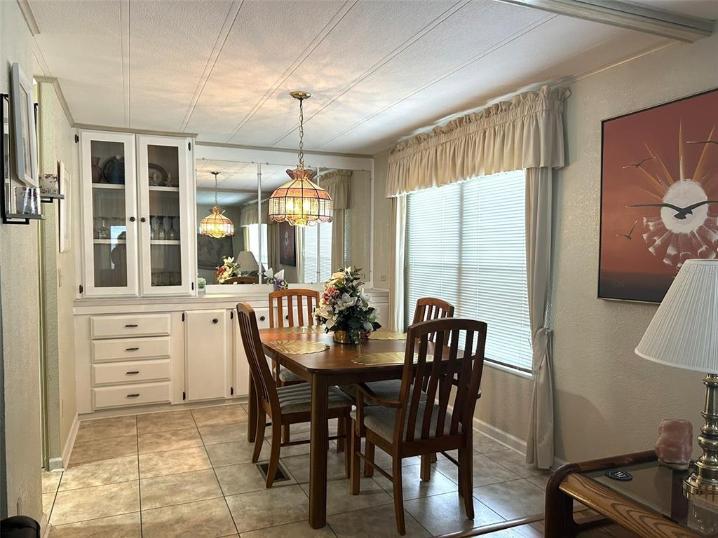A dining room features a wooden table, chairs, built-in cabinetry, a mirror, and tile flooring — 8407 WEATHERFORD AVENUE, BROOKSVILLE, FL