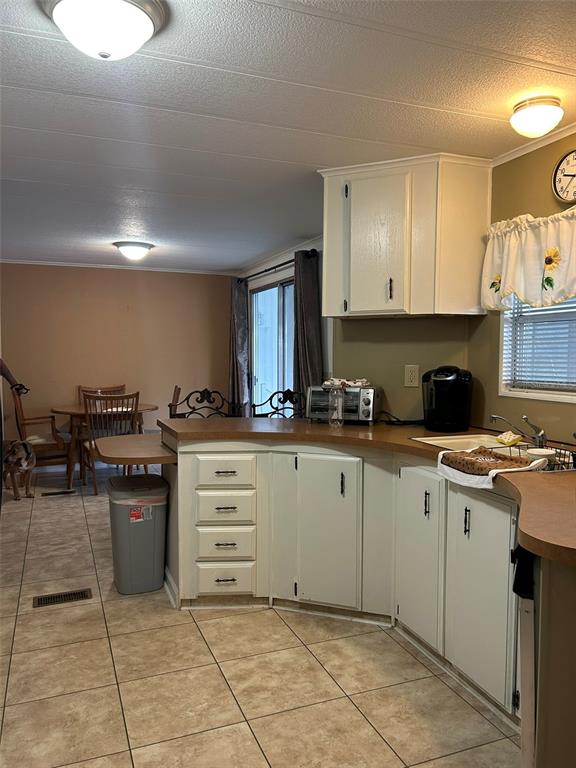 A kitchen with white cabinets and tan countertops opens into a dining area — 8407 WEATHERFORD AVENUE, BROOKSVILLE, FL