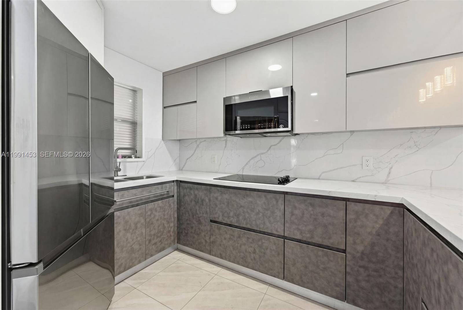 A modern kitchen features grey textured lower cabinets, glossy upper cabinets, and white marble countertops — 1750 W 46th St # 412, Hialeah FL 33012, HIALEAH, FL